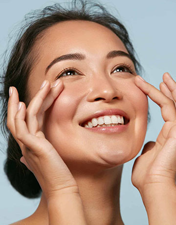 Smiling woman with clear skin touching the skin beneath her eyes